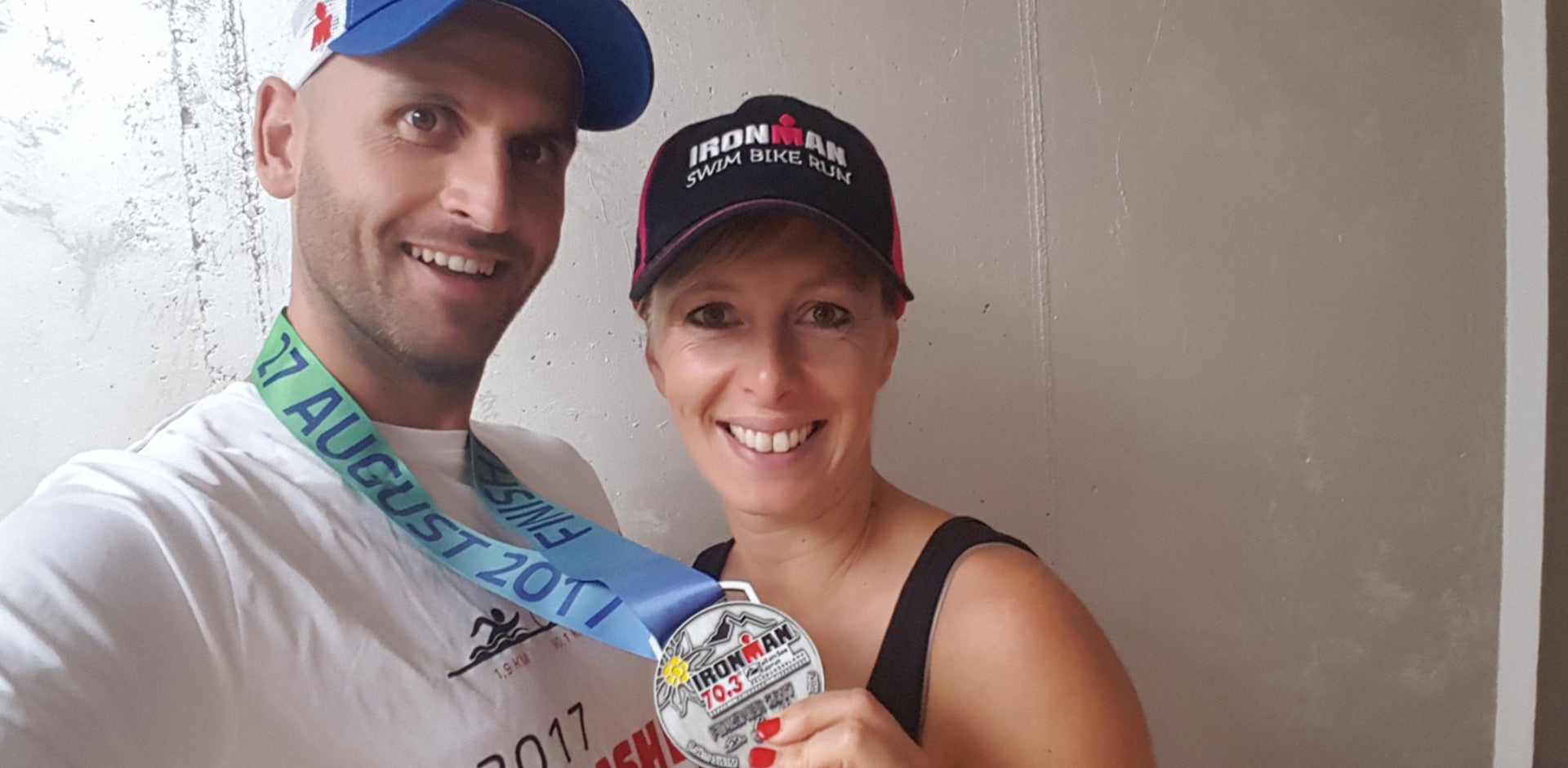 Klaus lächelt zufrieden mit seiner Medaille in der Hand und der Freundin an der Seite in die Kamera